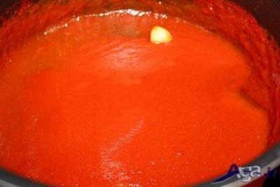 ریختن گوجه فرنگی صاف شده در درون قابلمه 