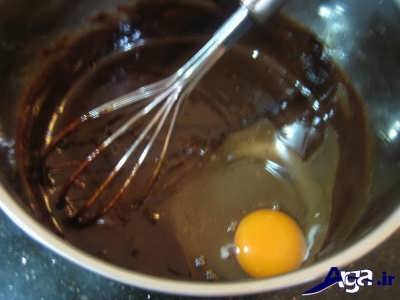 اضافه کردن تخم مرغ به مخلوط پودر کاکائو و شکر 