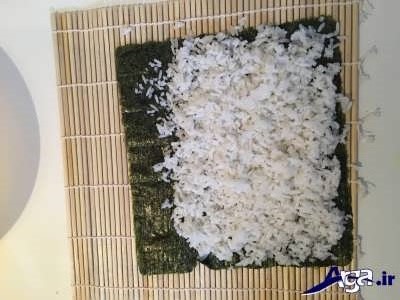 ریختن برنج بر روی برگه نوری سوشی 