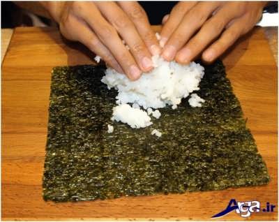 ریختن برنج بر روی برگه سوشی 