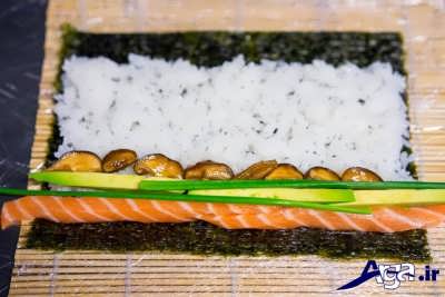 قرار دادن ماهی سالمون و قارچ و پیازچه بر روی برنج سوشی 