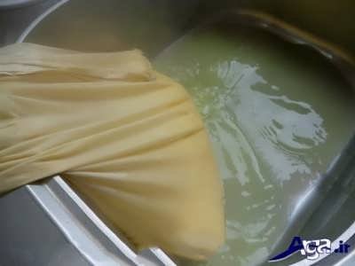 ریختن مخلوط شیر و سرکه در درون پارچه برای تهیه پنیر 
